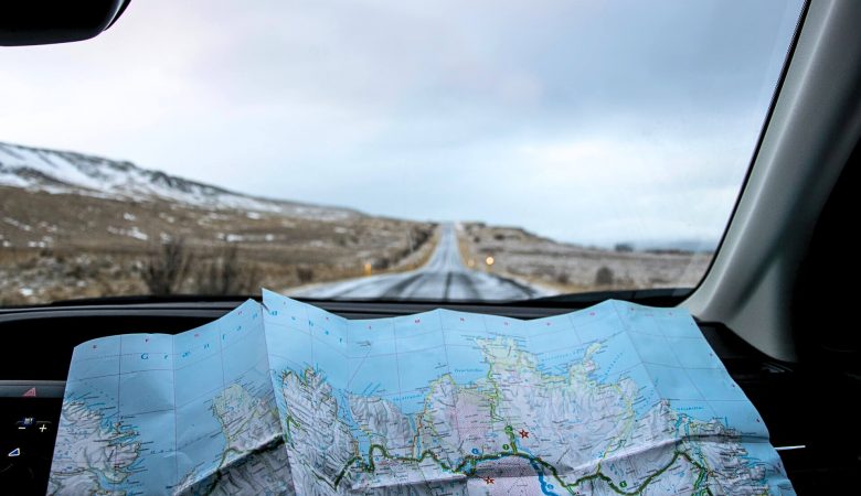 Un mapa extendido por el salpicadero de un coche, resaltando el espíritu aventurero de un viaje por carretera